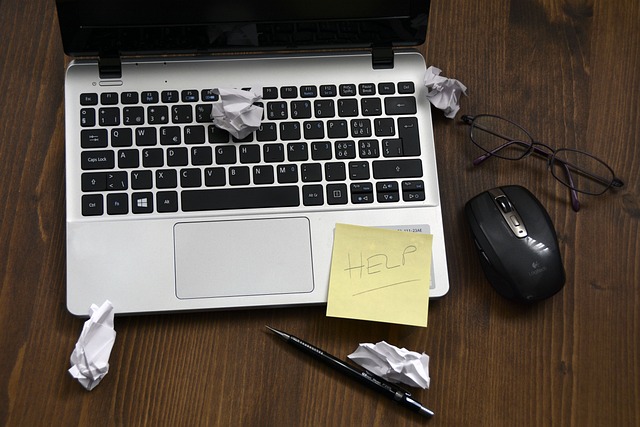 Laptop with litter and help written on a post-it note stuck on it.