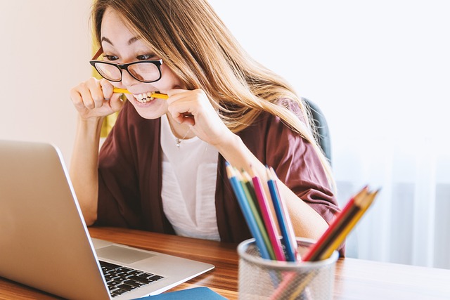 Someone looking at a computer , chewing on a pencil, representing IT frustration.