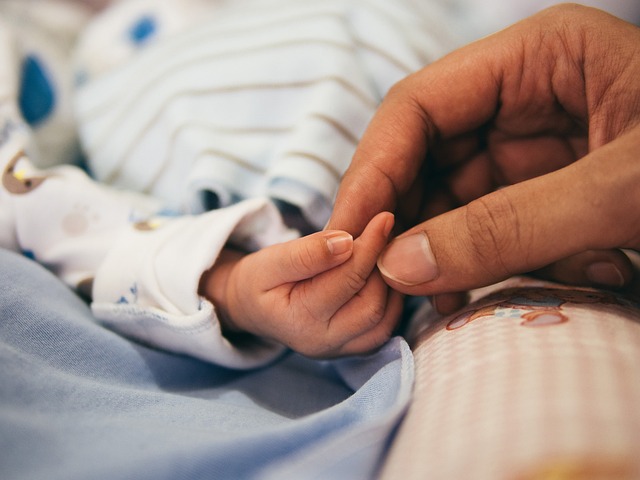 Adult and baby holding hands